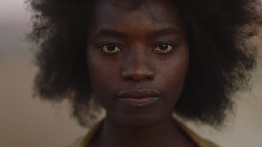Woman with afro faces the camera and makes eye contact at sunset