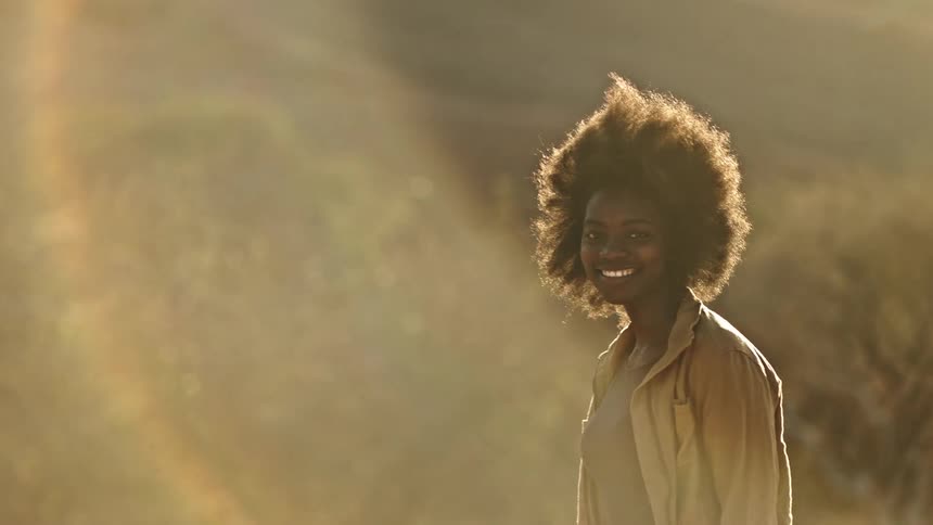 Sun flare portrait of a smiling young woman with afro