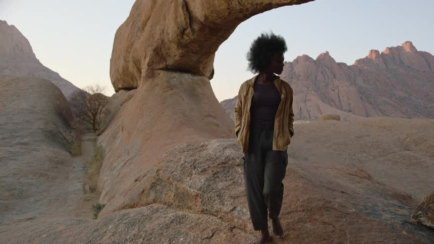 Woman walks barefoot across a rock formation