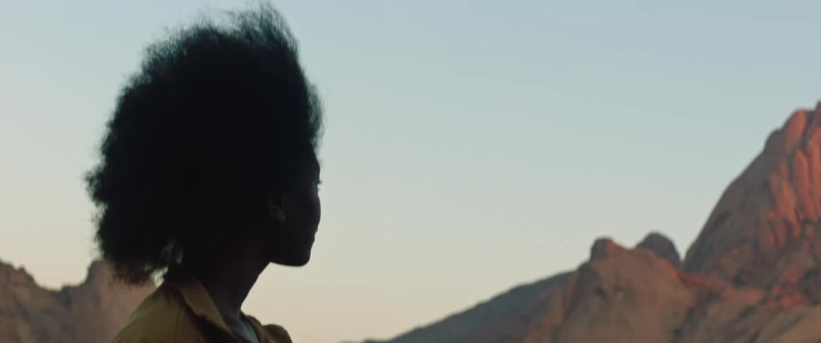 A woman looks out at a nearby peak while standing in the badlands
