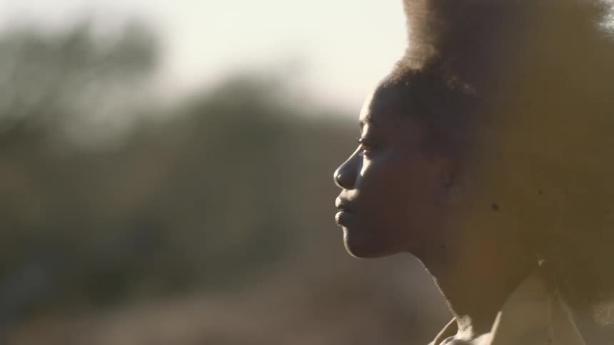 Moody portrait of a powerful black woman at sunset turning and looking directly into the camera