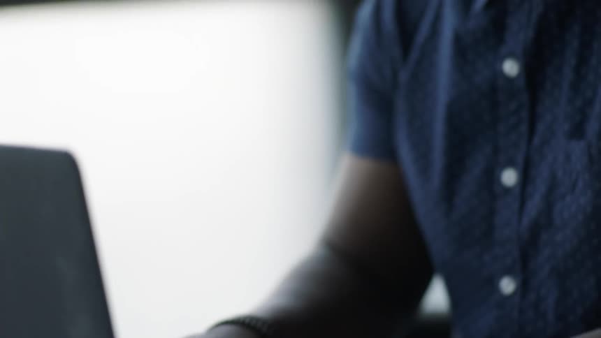 A man is typing on a laptop keyboard