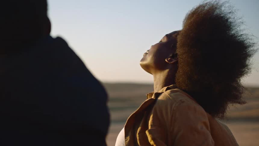 Young woman leans her head back and closes her eyes to enjoy the warmth of the sun