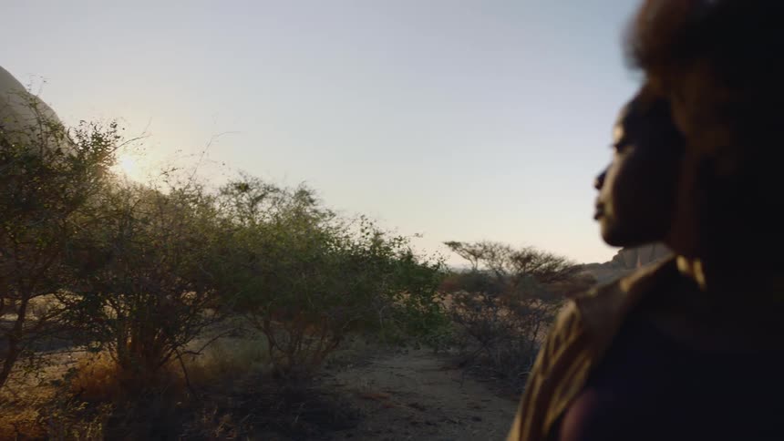 A woman in the desert stops to take in the view in a desert at dusk