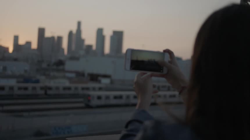 A woman is using her phone to photograph a view