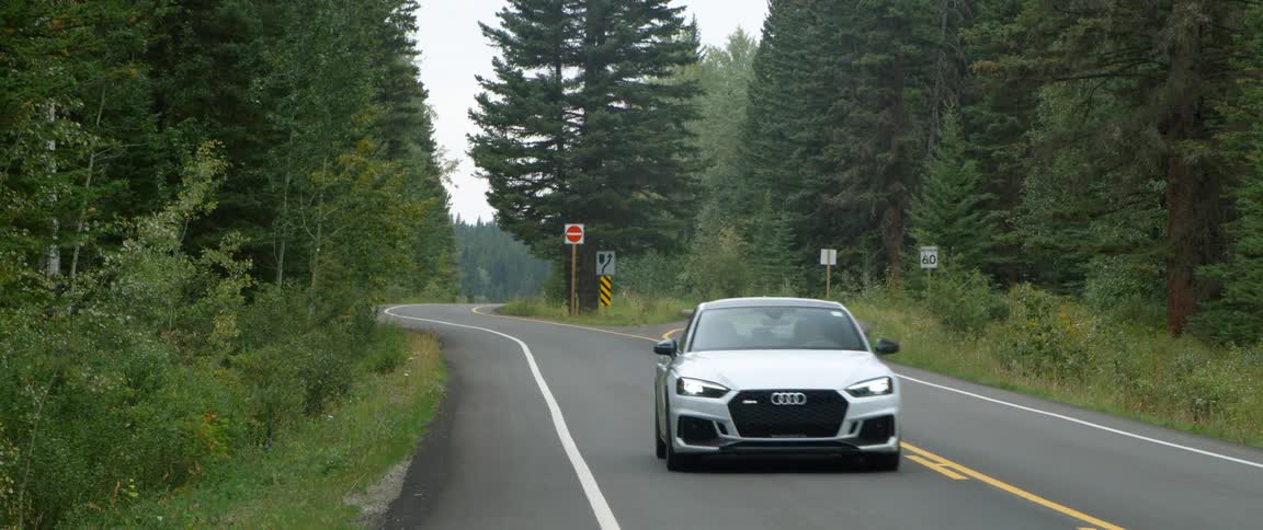 Car rides along highway passing through forest