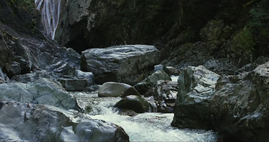A waterfall plunges down a cliff and rushes into a river