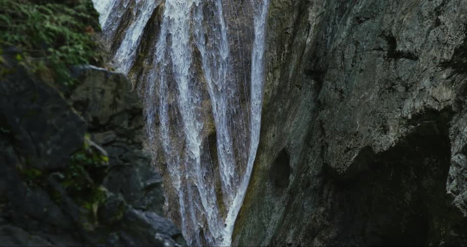 Water flows down the wall of a canyon during the day