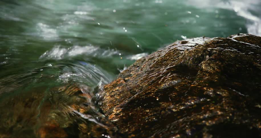 Water washes over a rock formation in a river during the day