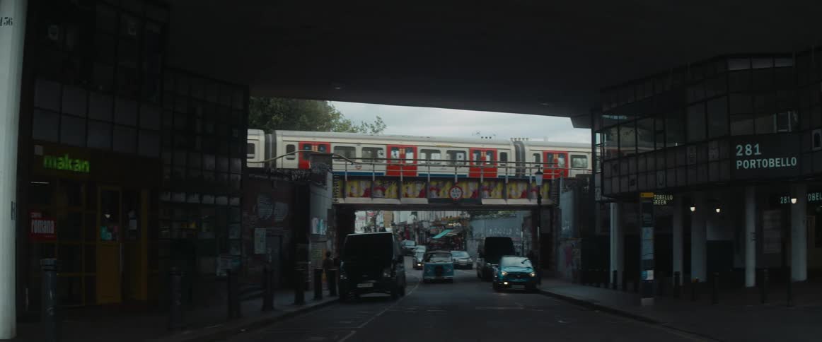 Traffic travels on a busy road as a subway train moves across an overpass
