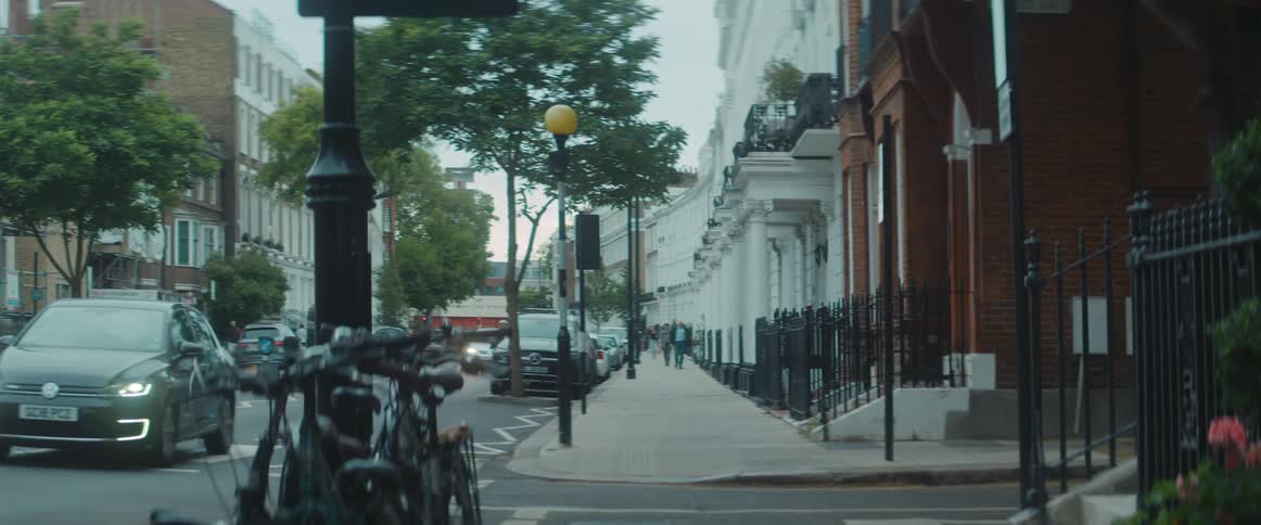 A downtown street with light traffic and people walking on the sidewalk