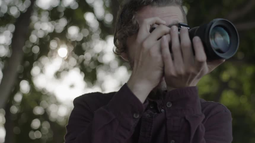 A person takes pictures under a tree