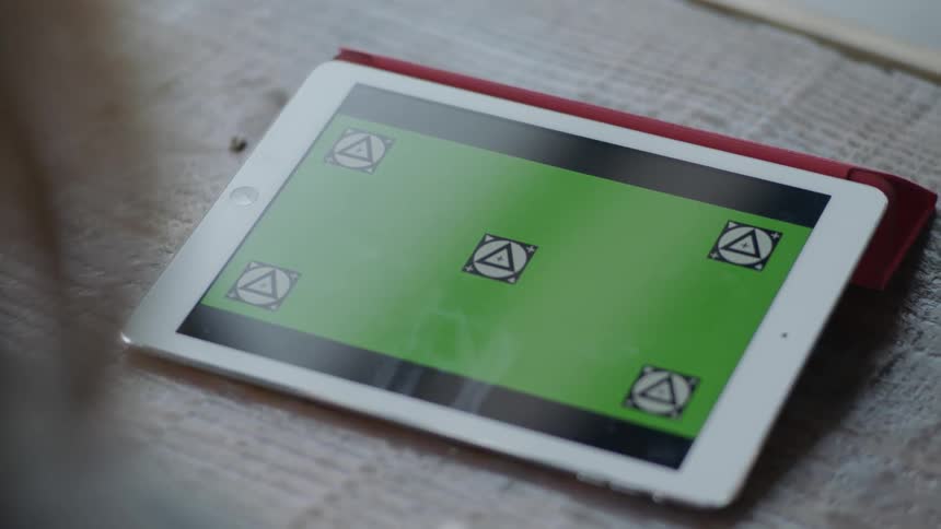 A person uses a tablet sitting next to a cup