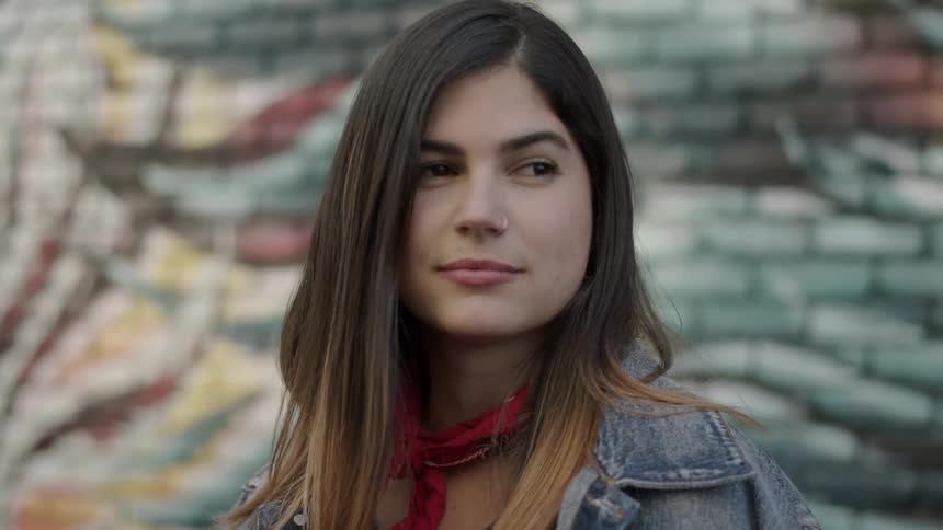 A woman is smiling in front of a brick wall