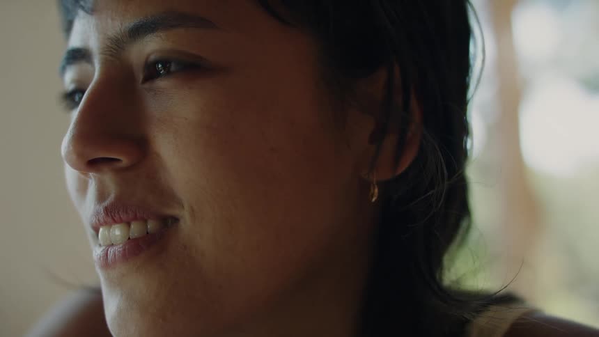 A young woman with dark brown hair and brown eyes is smiling