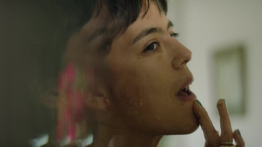A woman is putting on face cream in a mirror