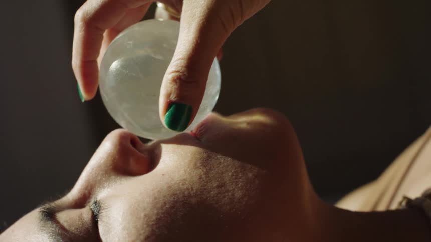 A woman getting her face massaged with a ball