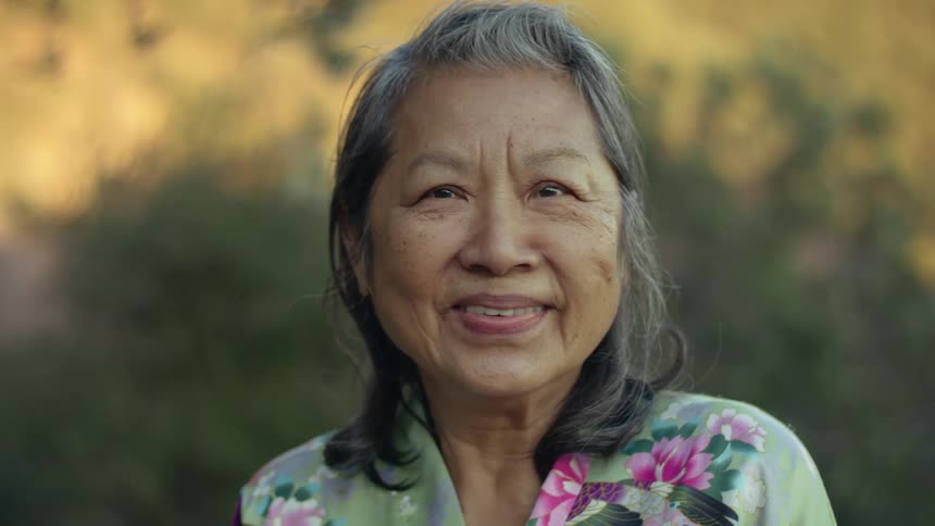 An elderly woman is outdoors and posing for the camera