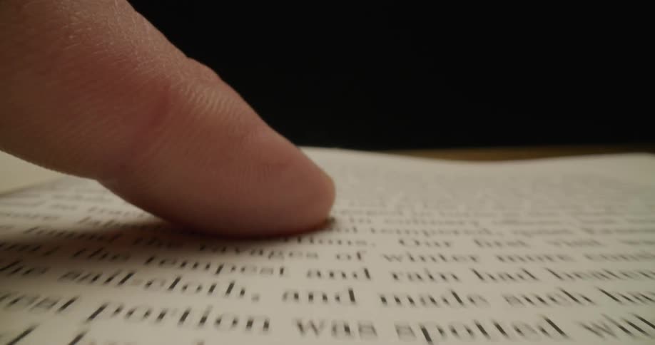 A finger travels over a page in a book to the top