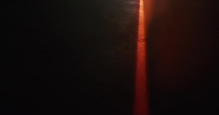 Red laser beam sweeping across ground is diffused by fog
