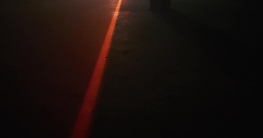 A red laser beam is shining outdoors at night