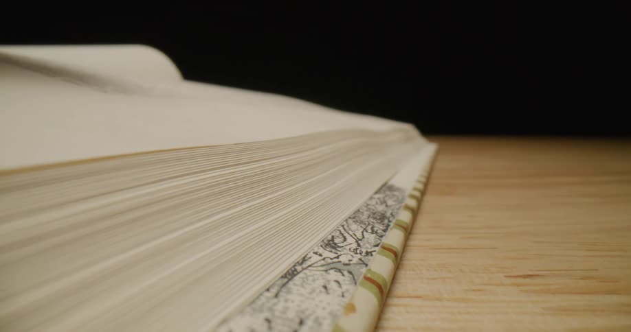 A person is turning a page of a book on a table