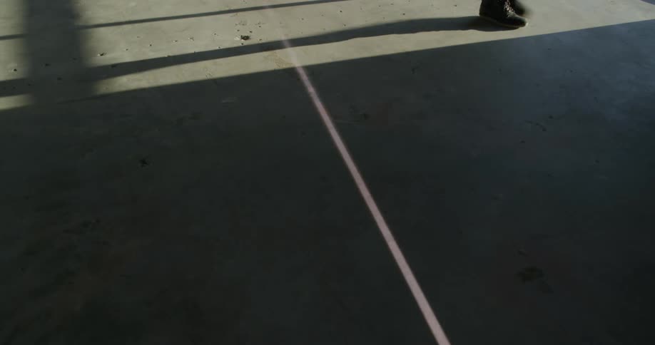 Person walks along pavement as beam crossed from shadow into light