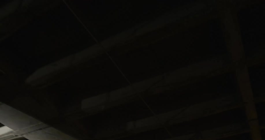A flashlight shines across an unfinished basement ceiling