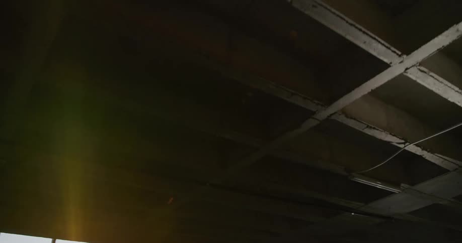 A flashlight shines across the unfinished ceiling of a basement