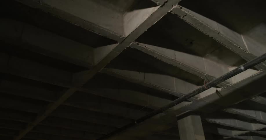 A light passes over a ceiling with joists and a pipe