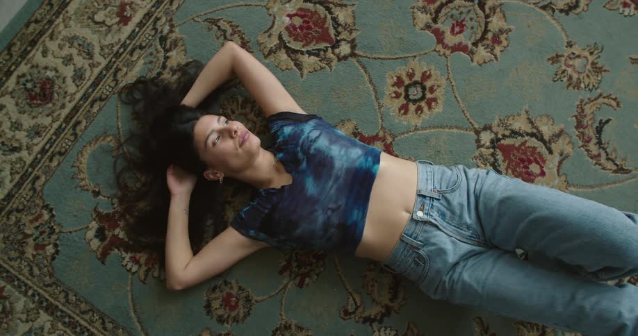 A woman lying down and relaxing on a rug indoors