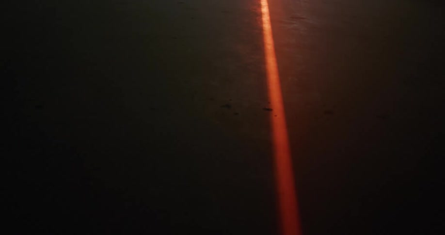 Red thick laser drawing a line on the concrete floor under white smoke