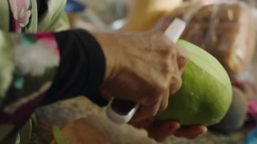 Woman peels fruit standing near counter