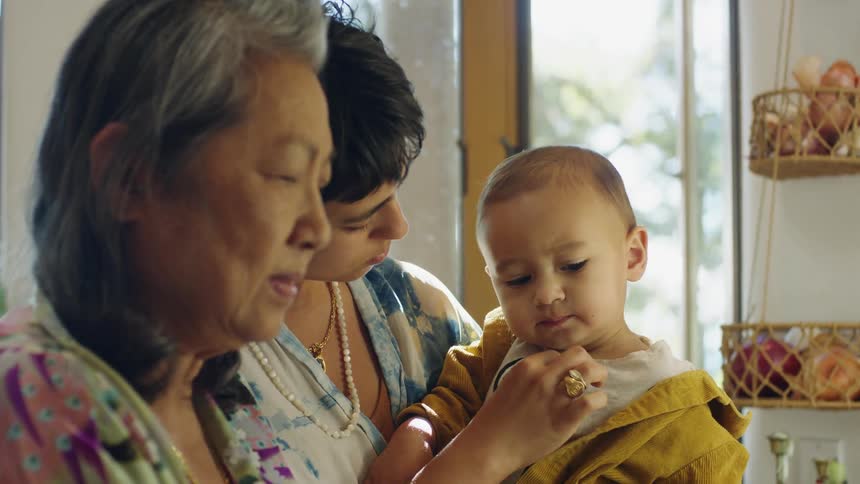 Three generations standing together in a kitchen mother daughter baby