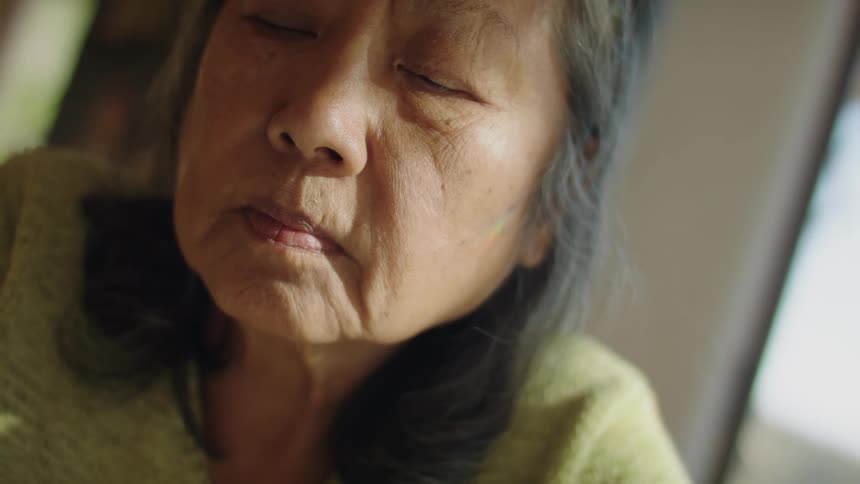 An elderly woman sitting with eyes closed