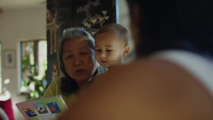 Grandmother reading a book to her grandson at home