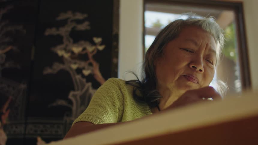 Woman with gray hair and green short sleeve shirt smiles and writes down in notebook