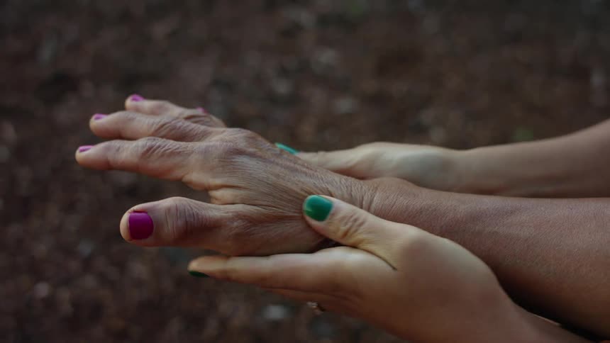 Younger woman massages and older womans hand