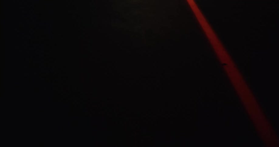 A red laser shining through pitch black