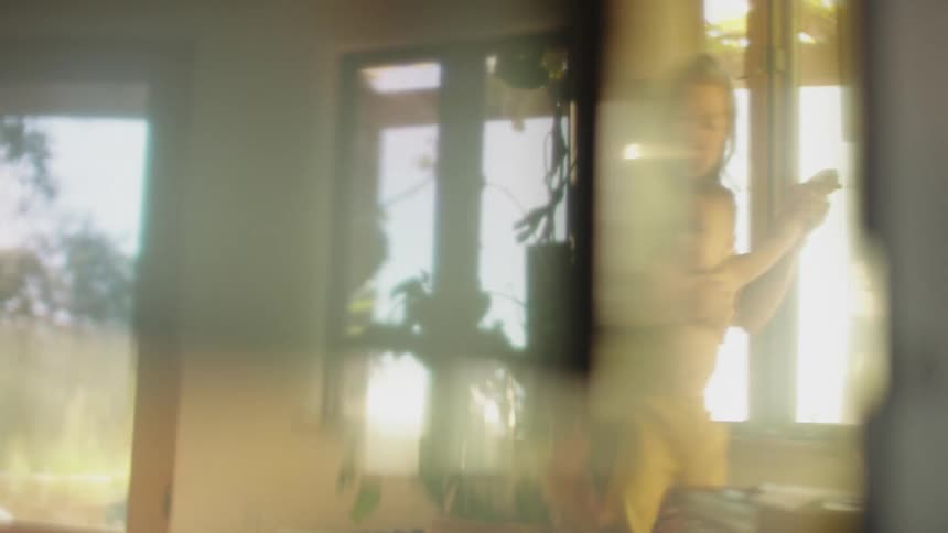 A grandmother playing with her grandson near sunny windows indoors