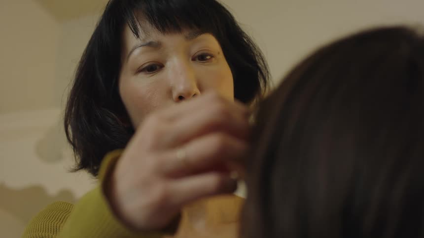 A woman is giving a facial to her daughter