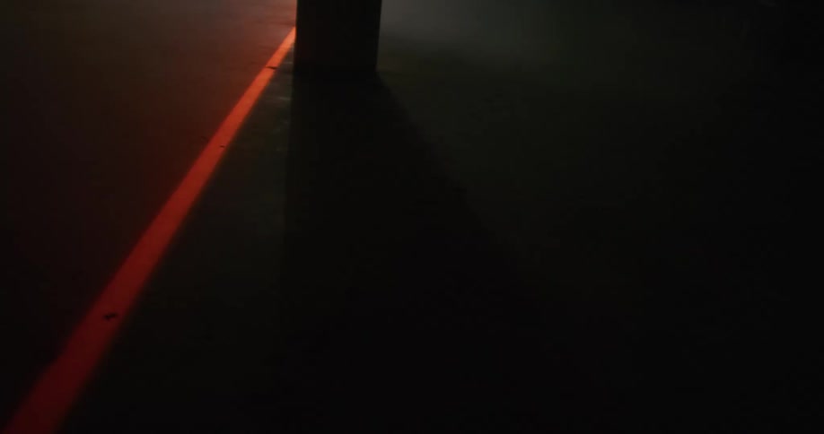 A bright orange line moves across the pavement at night