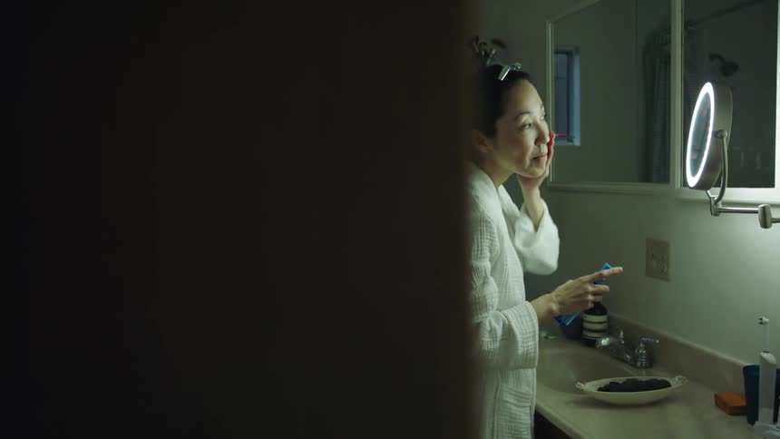A woman puts cream on her face