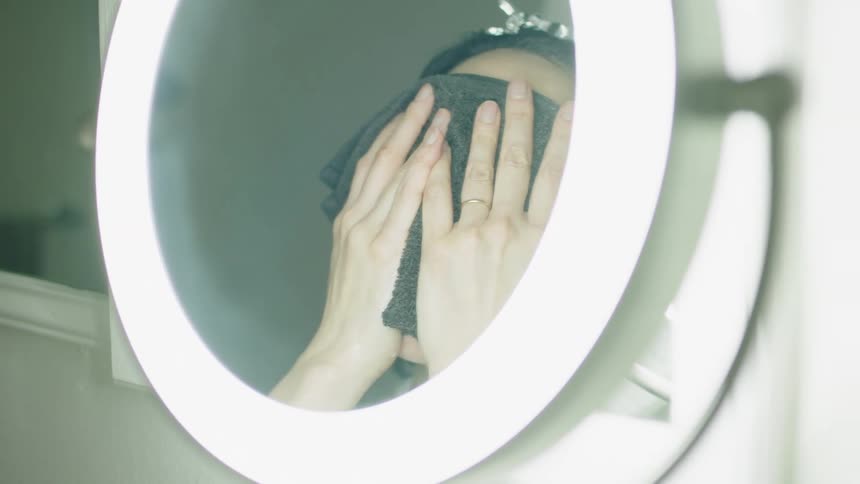 Woman views her face in makeup mirror before putting towel over face