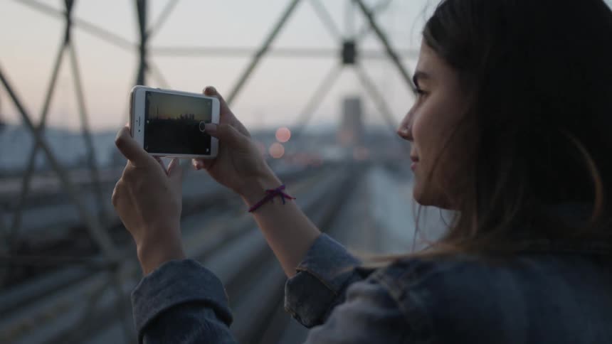 A woman is photographing with her phone on a windy day