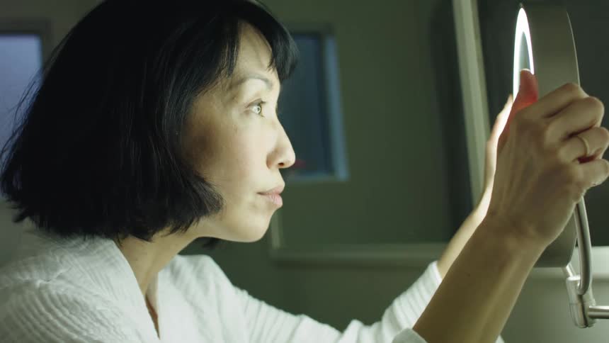 A woman is looking at her reflection in a mirror