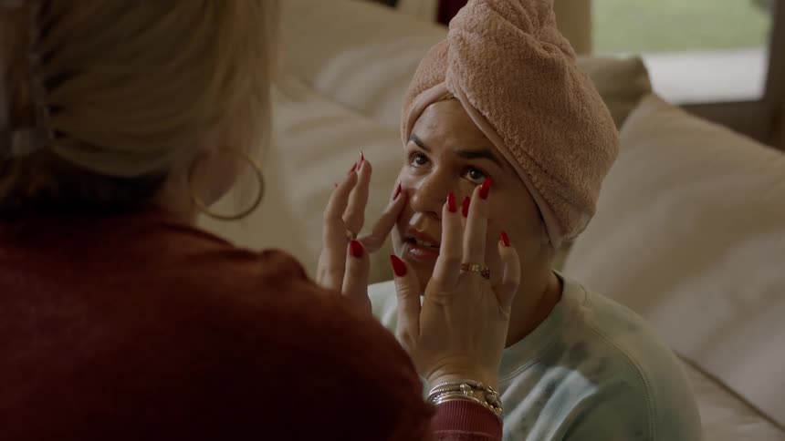 A woman sits on cushions as she gets a facial massage