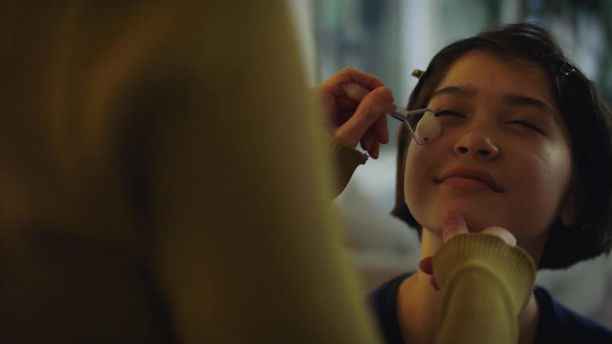 Woman rubs the cheeks of a young girl with a massaging tool