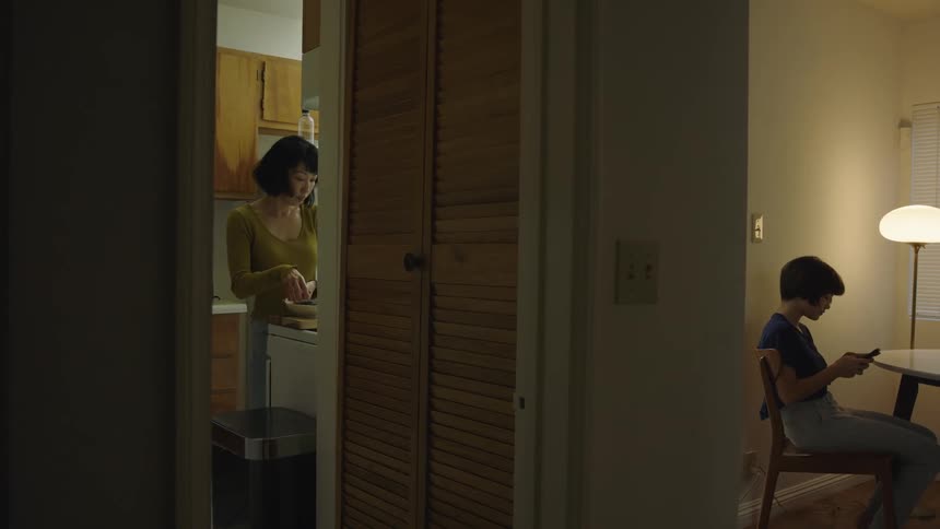 Mother prepares meal in kitchen before setting it on table in front of daughter