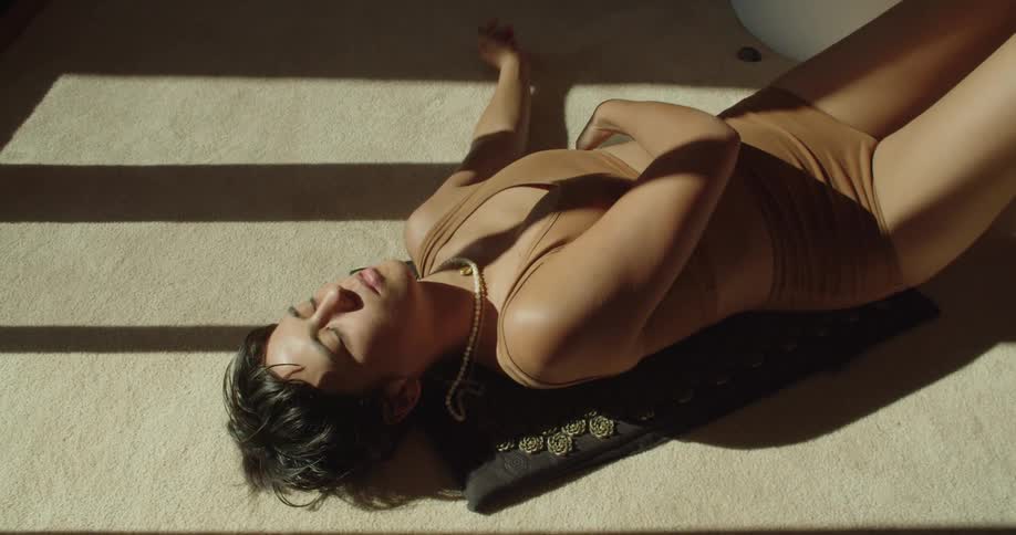 A young woman lies on a mat and rolls a small crystal ball over her stomach